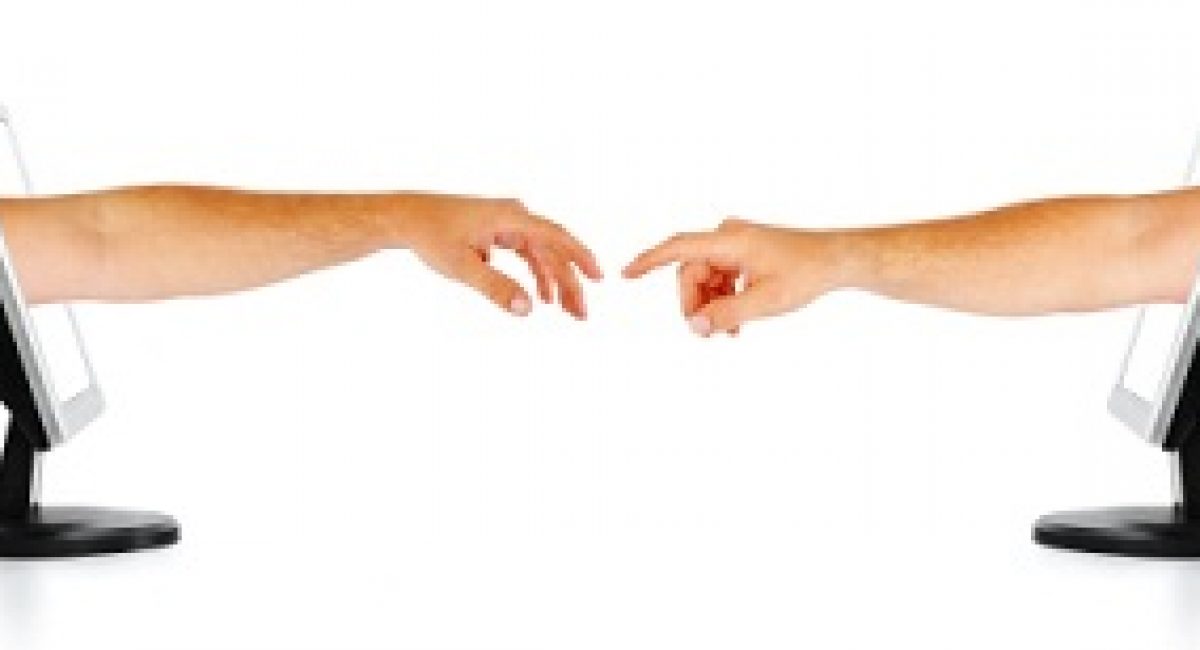 Two human hands coming out two seperate computer monitors, reaching out for each other. Isolated on a white background